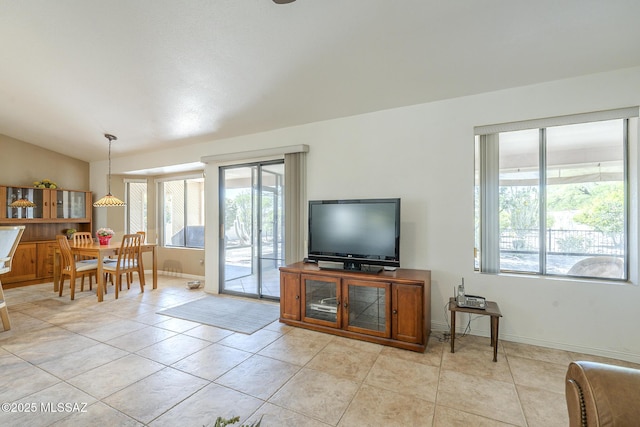 living room featuring lofted ceiling, baseboards, and light tile patterned flooring