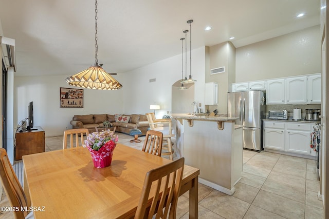 dining area with light tile patterned floors, a toaster, a high ceiling, visible vents, and recessed lighting