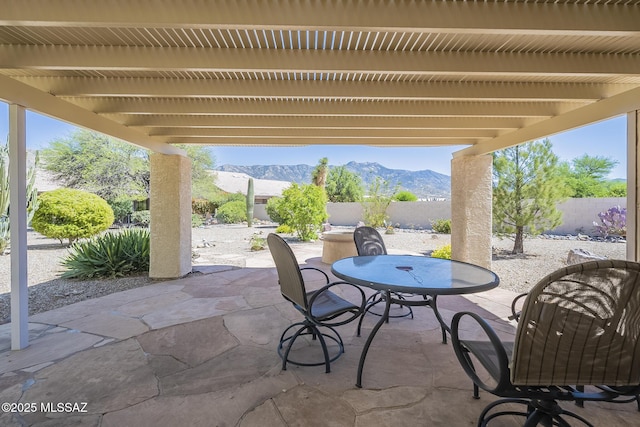 view of patio with outdoor dining area, a fenced backyard, and a mountain view