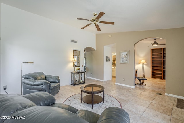 living area with arched walkways, light tile patterned flooring, vaulted ceiling, visible vents, and a ceiling fan
