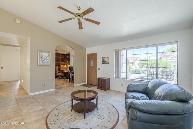 living room featuring lofted ceiling, a ceiling fan, arched walkways, light tile patterned flooring, and baseboards