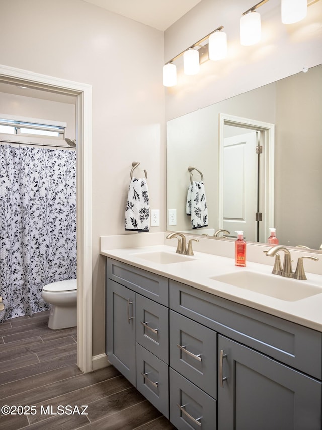 bathroom with double vanity, a sink, wood finished floors, and toilet