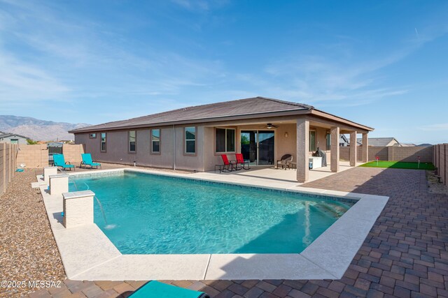 view of pool featuring a fenced backyard, a fenced in pool, a mountain view, a patio area, and a ceiling fan