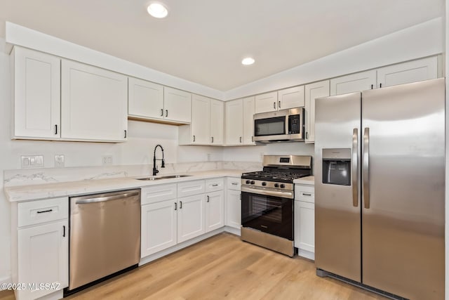 kitchen featuring white cabinets, light wood-style floors, a sink, and appliances with stainless steel finishes