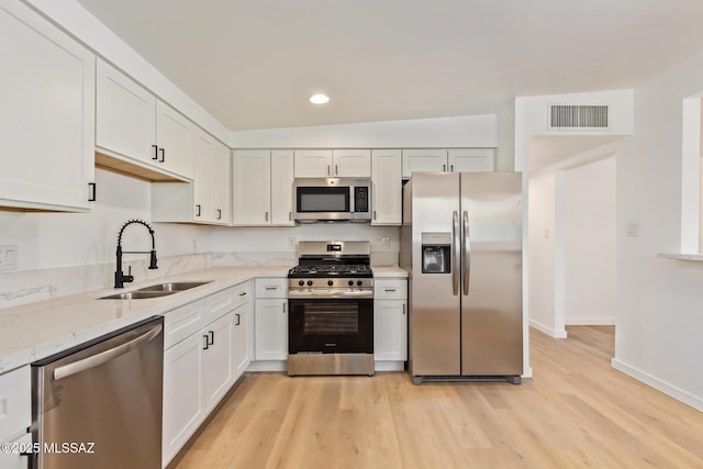kitchen featuring a sink, visible vents, light wood-style floors, and stainless steel appliances
