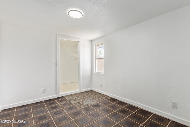 empty room with a textured ceiling and baseboards
