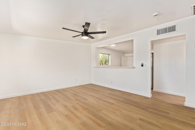 spare room featuring baseboards, light wood finished floors, ceiling fan, and visible vents