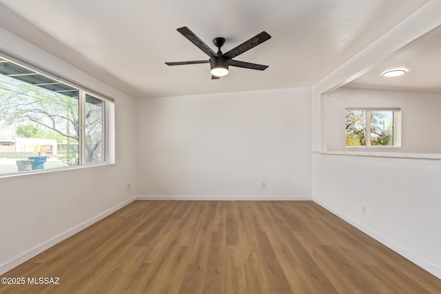 empty room featuring wood finished floors, baseboards, and a ceiling fan