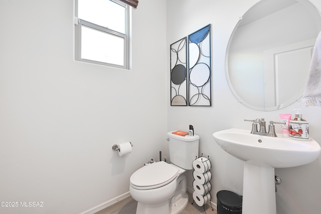 bathroom with toilet, baseboards, and a sink