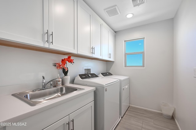 clothes washing area with cabinet space, independent washer and dryer, visible vents, and a sink