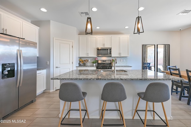 kitchen featuring visible vents, decorative backsplash, stainless steel appliances, and a sink