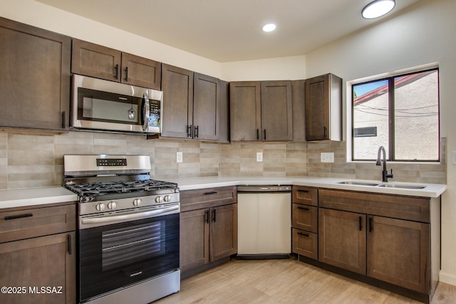 kitchen featuring appliances with stainless steel finishes, a sink, light wood-style flooring, light countertops, and recessed lighting