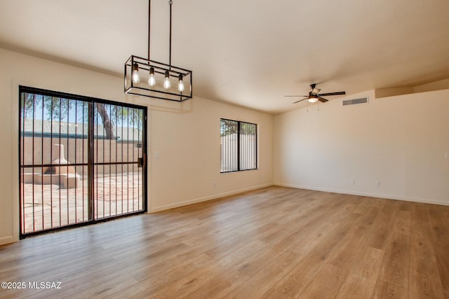 spare room with a ceiling fan, light wood finished floors, and baseboards