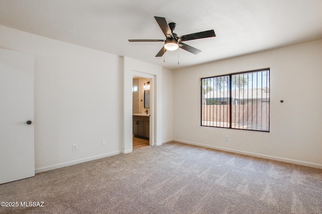 unfurnished bedroom featuring carpet floors, baseboards, ensuite bath, and ceiling fan