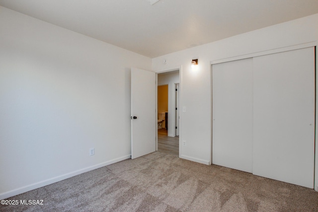 unfurnished bedroom with carpet floors, a closet, and baseboards