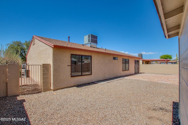 back of house with fence, stucco siding, a patio area, and central AC