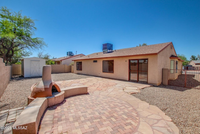 back of property featuring a storage shed, central air condition unit, a patio area, a fenced backyard, and an outbuilding