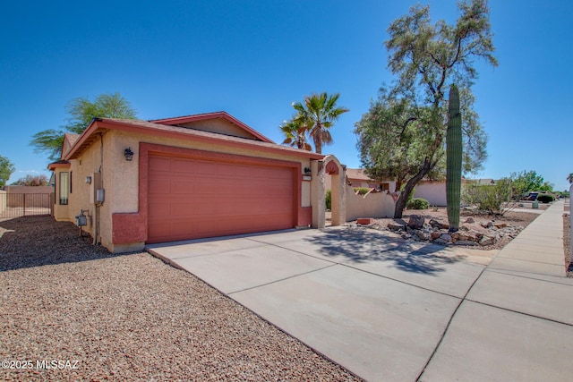 view of front of property with a garage, fence, stucco siding, and concrete driveway