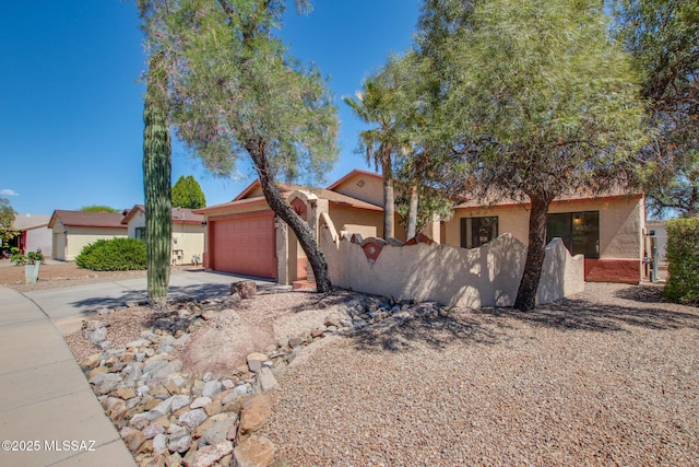 view of front facade with stucco siding, an attached garage, concrete driveway, and fence