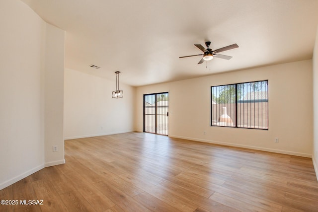 spare room with a ceiling fan, light wood-style floors, and baseboards