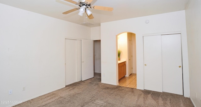 3581 W Avenida Vera Cruz, Tucson, AZ 85746 - unfurnished bedroom featuring light carpet, arched walkways, two closets, and ensuite bathroom