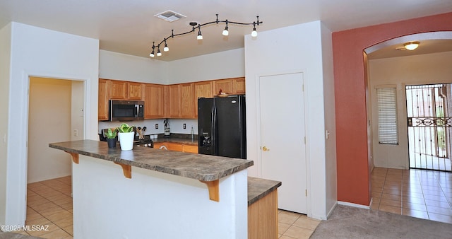 3581 W Avenida Vera Cruz, Tucson, AZ 85746 - kitchen featuring stainless steel microwave, black fridge, light tile patterned flooring, arched walkways, and dark countertops