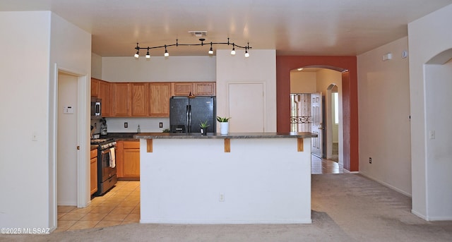 3581 W Avenida Vera Cruz, Tucson, AZ 85746 - kitchen with appliances with stainless steel finishes, arched walkways, a center island, dark stone countertops, and light colored carpet