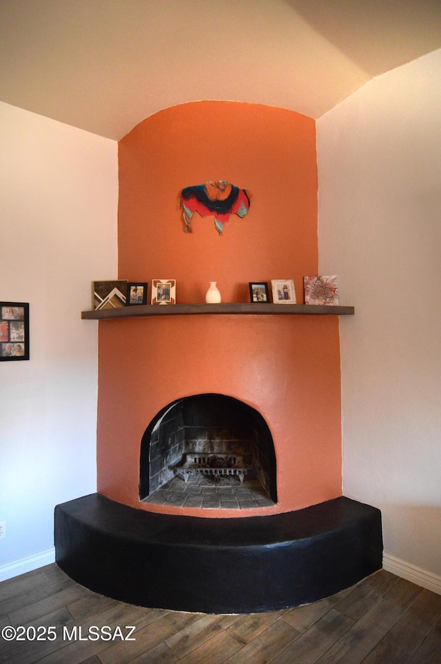 interior details featuring baseboards, a fireplace with raised hearth, and wood finished floors