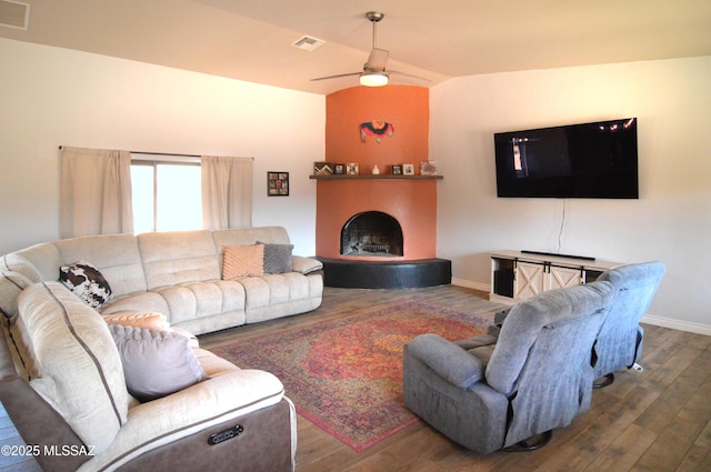 living area featuring ceiling fan, visible vents, wood finished floors, baseboards, and a fireplace with raised hearth
