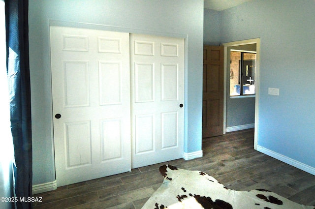 unfurnished bedroom featuring baseboards and dark wood-type flooring