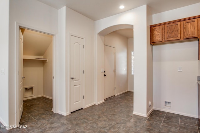 corridor featuring arched walkways, baseboards, and recessed lighting