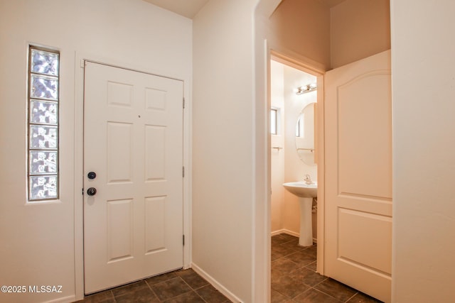 foyer with arched walkways, baseboards, and dark tile patterned flooring