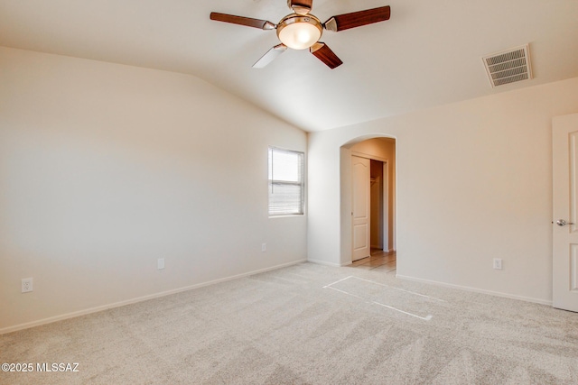 spare room featuring ceiling fan, arched walkways, light carpet, lofted ceiling, and visible vents
