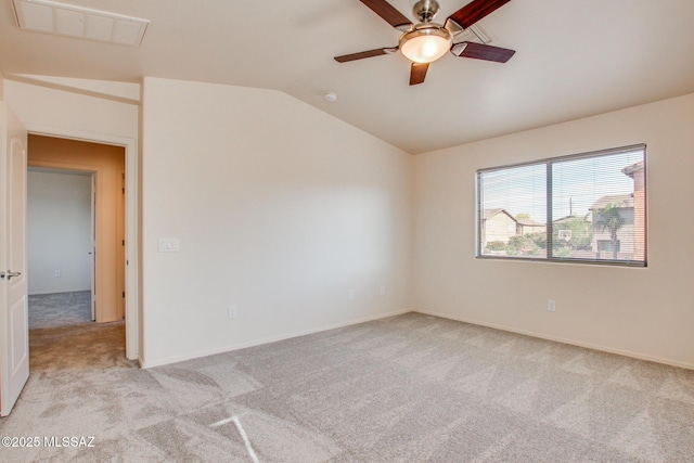 empty room featuring vaulted ceiling, baseboards, visible vents, light colored carpet, and a ceiling fan
