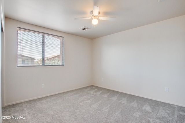 spare room featuring ceiling fan, visible vents, baseboards, and light carpet