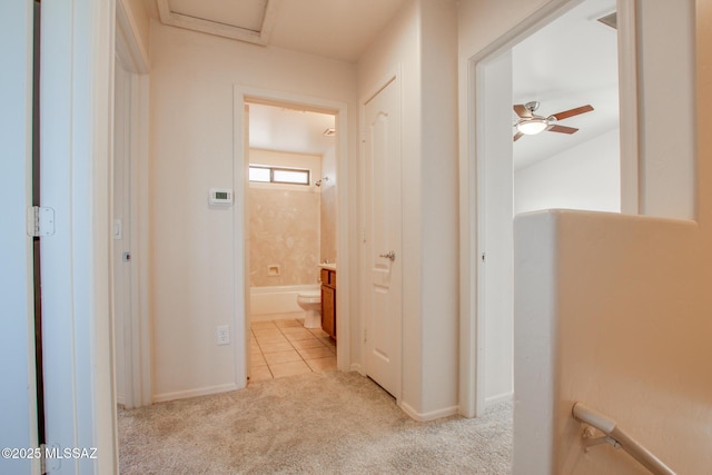 corridor featuring light colored carpet, baseboards, and light tile patterned flooring