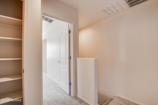 corridor with carpet, visible vents, and baseboards