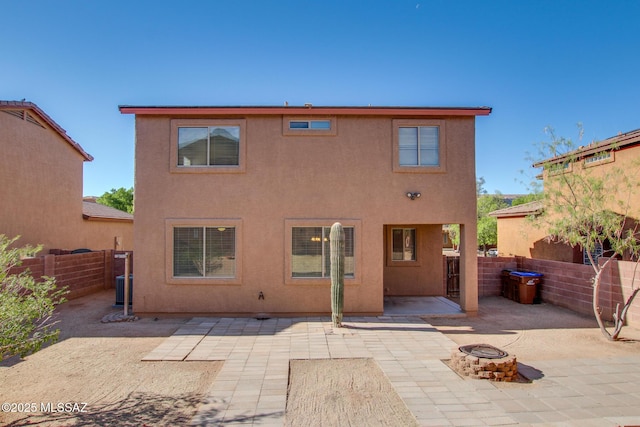 rear view of property with a patio area, an outdoor fire pit, and stucco siding