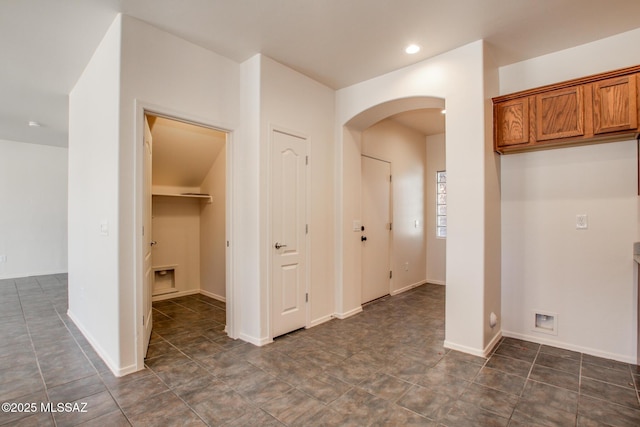 hallway with baseboards, arched walkways, and recessed lighting
