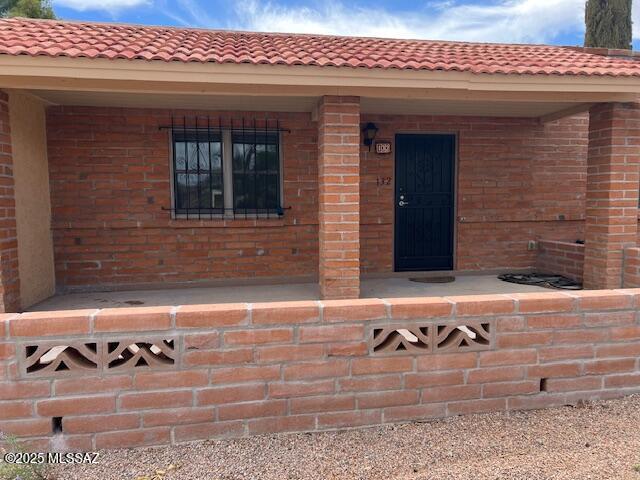 doorway to property with brick siding and a tiled roof