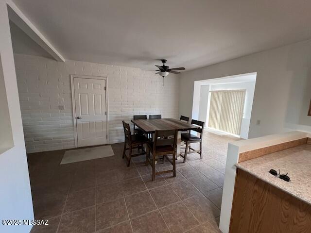 dining area featuring a ceiling fan and dark tile patterned flooring