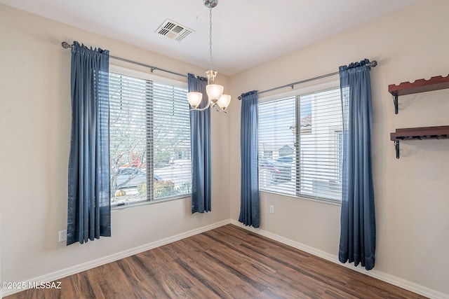 unfurnished room with a chandelier, visible vents, baseboards, and dark wood finished floors