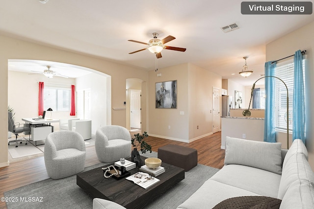 living room with arched walkways, wood finished floors, and ceiling fan