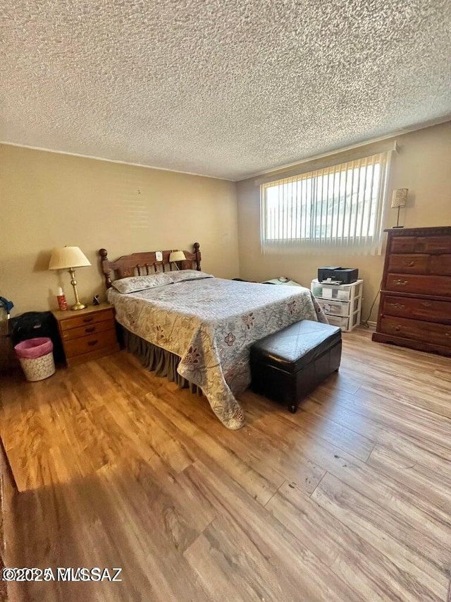 bedroom with a textured ceiling and wood finished floors