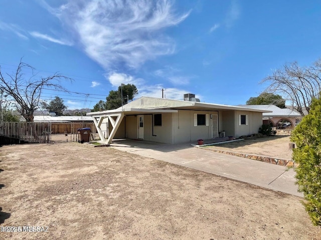 back of house featuring fence, an attached carport, and driveway