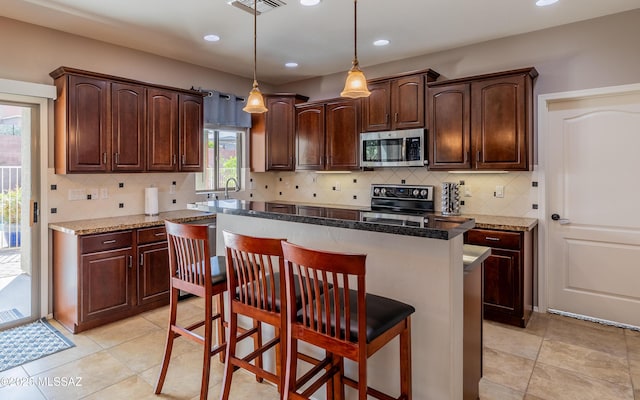 9125 S Crows Nest Ct, Tucson, AZ 85756 - kitchen with appliances with stainless steel finishes, a kitchen bar, a kitchen island, decorative backsplash, and recessed lighting