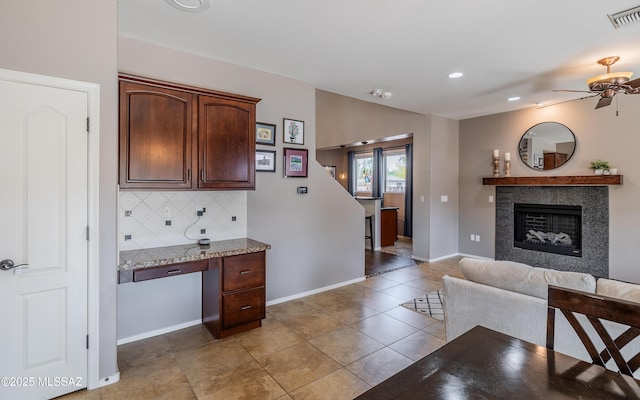 9125 S Crows Nest Ct, Tucson, AZ 85756 - kitchen with decorative backsplash, ceiling fan, light stone countertops, open floor plan, and baseboards