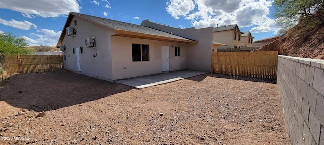 back of property with a fenced backyard, stucco siding, and a patio area