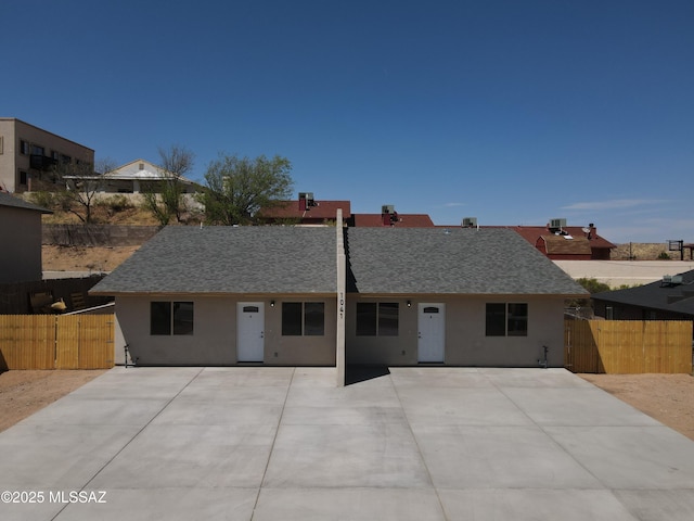 view of front facade featuring a shingled roof, fence, a gate, and stucco siding