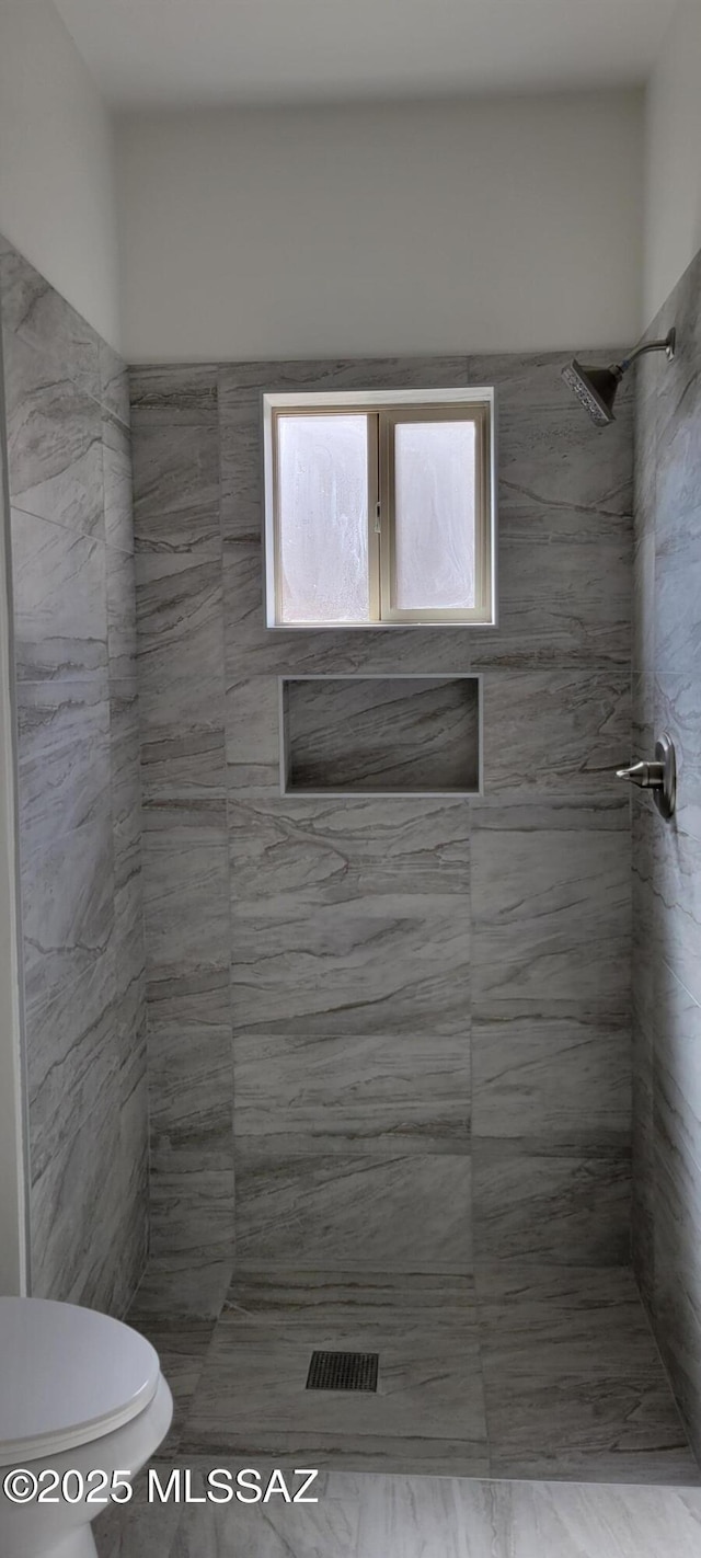 full bath with toilet and tiled shower